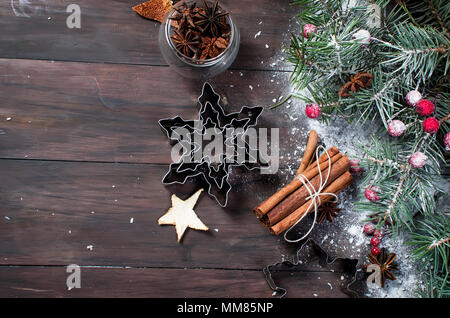 forms for biscuits, cinnamon sticks, anise and dried candied fruits on a wooden table.  Baking holiday cookies. Christmas baking background . Stock Photo