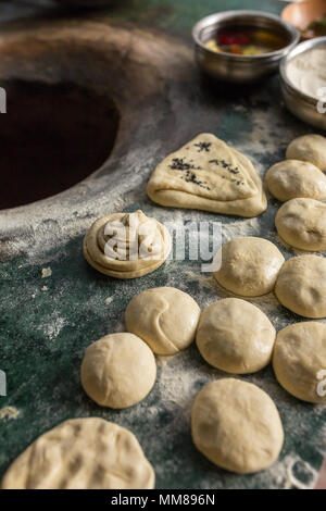 Ingredients for tandoori naan or roti - indian flat bread baked in clay oven. Oil, dough, flour and spices on the top of tandoori oven Stock Photo