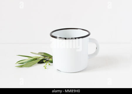 https://l450v.alamy.com/450v/mm89h0/styled-stock-photo-feminine-still-life-composition-with-blank-white-metal-coffee-enamel-mug-and-green-olive-branch-on-white-table-background-summer-rustic-scene-product-mockup-mm89h0.jpg