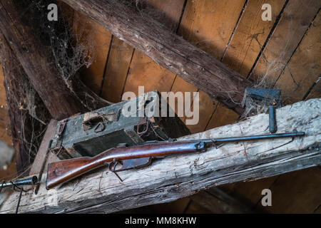 Old hunting rifle hanging on a wooden beam as display in an old farmhouse building Stock Photo