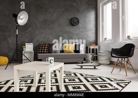 Cozy spacious modern family room. In the middle white coffee table with left cup and skateboard on the floor Stock Photo