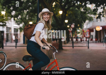 Attractive young woman cycling in the city. Female riding bicycle. Stock Photo