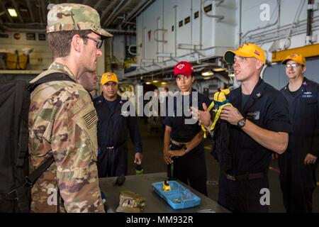 170917-N-KW492-010  CARIBBEAN SEA (Sept. 17, 2017) Damage Controlman 1st Class Benjamin Vangen , right, explains how to operate an emergency escape breathing device to Air Force Lt. Col. Jason Pfluke in the hangar bay aboard the amphibious assault ship USS Kearsarge (LHD 3). Kearsarge is evacuating service members assisting with relief efforts in the aftermath of Hurricane Irma from St. Thomas, U.S. Virgin Islands, in anticipation of Hurricane Maria. The Department of Defense is supporting the Federal Emergency Management Agency, the lead federal agency, in helping those affected by Hurricane  Stock Photo