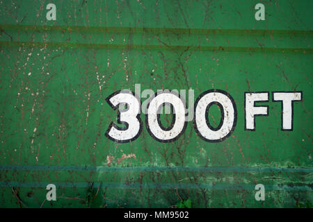 A vine covered bright green wall with the words "300 ft" painted on it Stock Photo