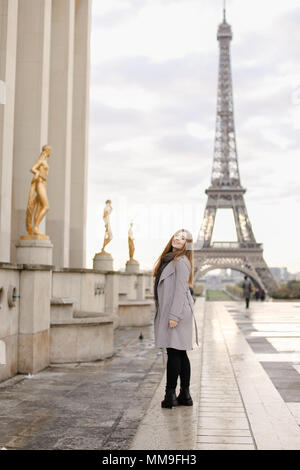 European woman standing on Trocadero square near gilded statues and Eiffel Tower. Stock Photo
