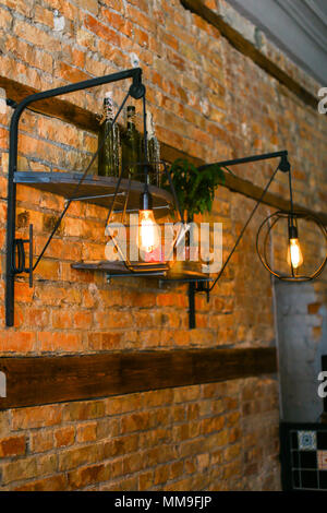 Brick wall with lamps and inscription in unusual cafe. Stock Photo