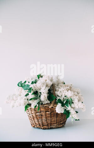 Bouquet of fresh white lilac flowers in wicker basket on wooden  Stock Photo