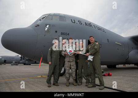 Members of the C-130J delivery team pose for a photo in front of a C-130J Super Hercules at Yokota Air Base, Japan, Sept. 20, 2107. This is the fifth C-130J delivered to Yokota and the first from Ramstein Air Base. Crewmembers from the 36th Airlift Squadron flew halfway around the world to deliver the aircraft here. Yokota serves as the primary Western Pacific airlift hub for U.S. Air Force peacetime and contingency operations. Missions include tactical airland, airdrop,aeromedical evacuation, special operations and distinguished visitor airlift. (U.S. Air Force photo by Yasuo Osakabe) Stock Photo