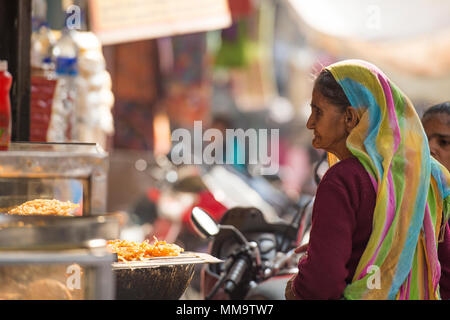 VARANASI - INDIA - 14 DECEMBER 2017. A poor old woman is about to buy some Jalebi in a stall in the alleys of Varanasi, India. Jalebi, also known as Z Stock Photo
