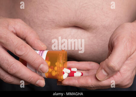 Man with overweight takes medication, conceptual image Stock Photo