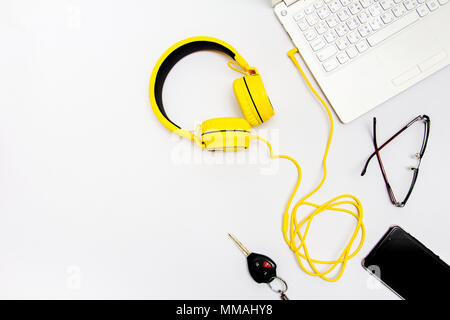 Yellow headphones, notebooks, car keys, glasses and mobile. Placed on a white background. Stock Photo