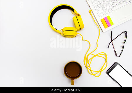 Yellow earphones, notebooks, coffee cups, glasses and mobile. Placed on a white background. Stock Photo