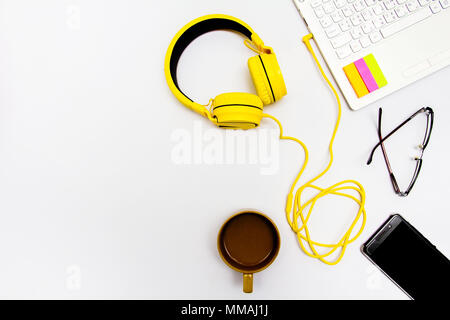 Yellow earphones, notebooks, coffee cups, glasses and mobile. Placed on a white background. Stock Photo