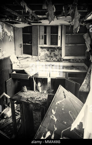 The inside of an abandoned house's kitchen. This house has been abandoned for years and is showing the signs of vandalism and deterioration. Stock Photo