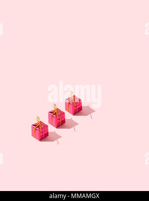 Three small gift boxes organized in a row over pink background Stock Photo
