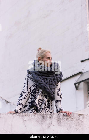 Blonde young beautiful fashion girl wearing aztec black and white jacket and knitted grey vest scarf. Festival outfit. Lifestyle street fashion trend Stock Photo