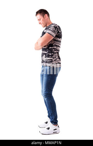 Sad pensive young man with crossed arms looking down. Full body length ...