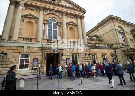 queues of tourists waiting in line to enter the roman baths complex abbey churchyard Bath England UK Stock Photo