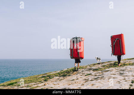 Couple of climbers with dog hiking with crash pads on the back to climb at the coast Stock Photo