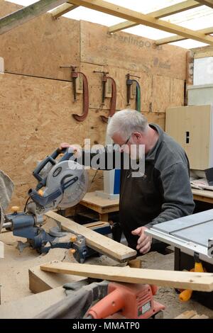 A senior retired man passes time making things from wood in his little homemade workshop in Glasgow, Scotland, UK Stock Photo