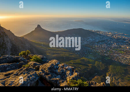 Sunset with aerial view over Cape Town and its urban skyline and the famous lion's head mountain peak as seen from the Table Mountain, South Africa.