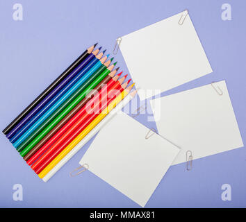 Blanks sheet of papers and color pencils on violet background for Projects and Announcements. Stock Photo