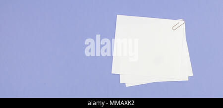 Blank note papers label with clip on purple background. Stock Photo