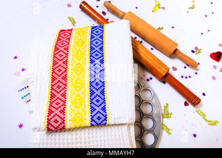 Kitchen towels with Romanian tricolor and a wooden spoon or stick, tools for the dumplings preparation. Shape of dumplings & stick, on background of t Stock Photo