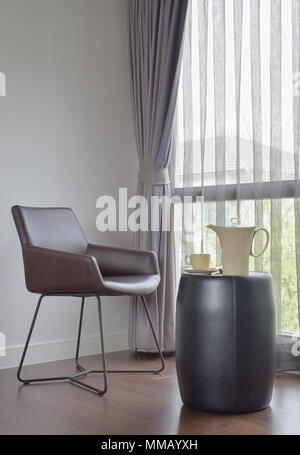 Dark brown chair at the corner with ceramic coffee set on the table Stock Photo