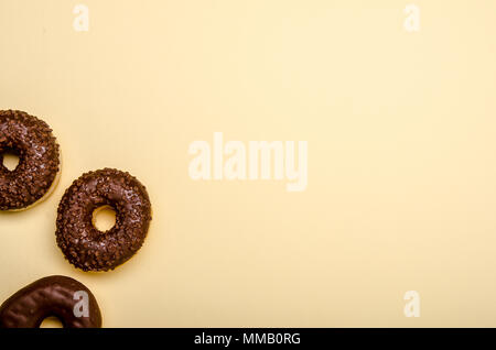 three chocolate donuts on beige background, copy space Stock Photo