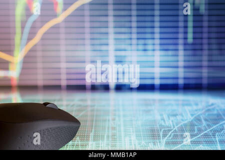 Computer mouse on futuristic display with defocused stock market graphs. Internet trading and modern business theme Stock Photo