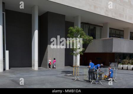 While workmen attend to a job, ladies take a sunshine break outside the Royal Festival Hall on the Southbank, on 9th May 2018, in London, England. Stock Photo