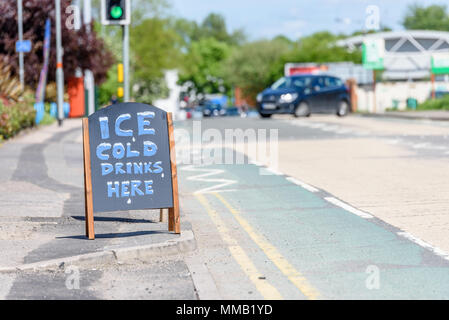 Day view Ice Cold Drinks Here wooden sign on British sidewalk. Stock Photo
