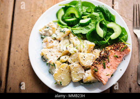 Salmon with wholegrain mustard, potato salad and spinach and cucumber salad with vinaigrette Stock Photo