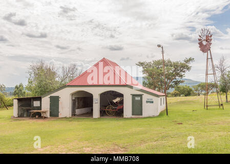 DUNDEE, SOUTH AFRICA - MARCH 21, 2018: The coach house, an historic building at the Talana museum, Dundee. A horse drawn coach and windmill are visibl Stock Photo