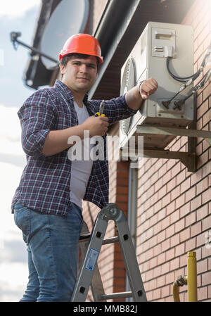 Portrait of young air conditioner engineer checking conditioning system Stock Photo