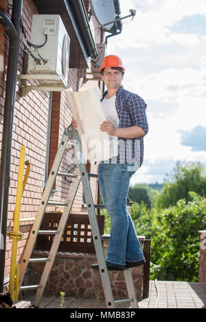 Electrician looking at blueprints and plan of air conditioning system at house Stock Photo