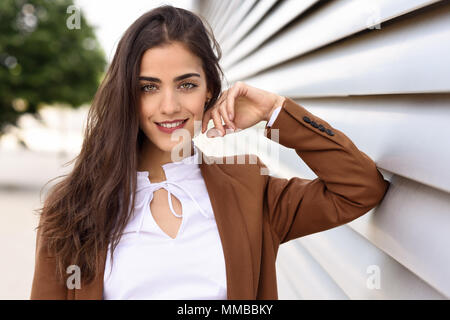 Young woman with nice wavy long hair. Beautiful girl wearing formal wear. Young female with brown jacket. Stock Photo