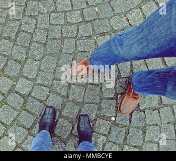 Legs with shoes of woman and man on a paved street background, top view Stock Photo