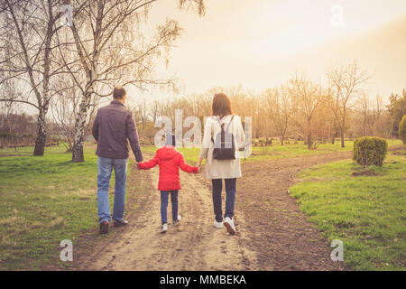 Happy young family spending time together outside in nature. parents holds the hands of a small children. Stock Photo
