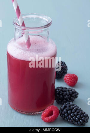 Healthy Raspberry Smoothie in Glass Bottle with Red and White Straw, three blackberries, two raspberries, wooden background Stock Photo