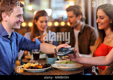 Group Of Friends Paying For Meal In Restaurant Stock Photo