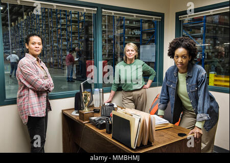 Team portrait of two African American female warehouse workers and one female caucasian warehouse  worker in an office in the middle of a large distri Stock Photo