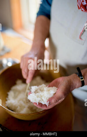 Close up of woman standing at a table in a kitchen, making sushi. Stock Photo