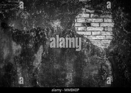 Background of a weathered and damaged dark gray plastered wall with in black and white vignette. Plaster is partly peeled off revealing old bricks. Stock Photo