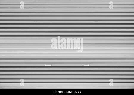 Full frame background of a closed roller door (or roller shutter, sectional overhead door, roll up or rolling garage door) in black and white Stock Photo