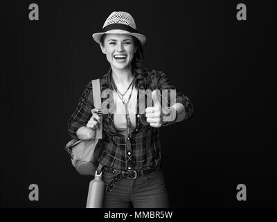 Searching for inspiring places. smiling young traveller woman with backpack showing thumbs up on background Stock Photo