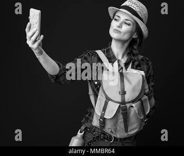 Searching for inspiring places. young traveller woman in a plaid shirt with smartphone taking selfie isolated on background Stock Photo