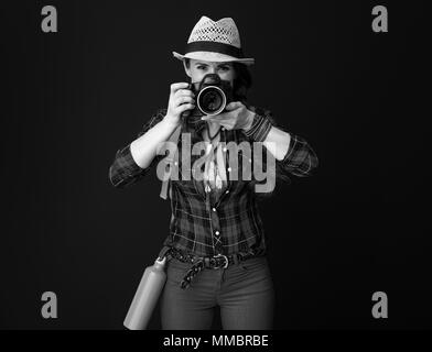 Searching for inspiring places. young traveller woman in a plaid shirt with digital camera taking photo against background Stock Photo