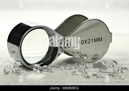 brilliant cut diamonds with folding magnifier on wooden background Stock Photo